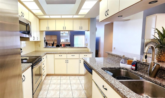 kitchen featuring cream cabinetry, stainless steel appliances, stone counters, and sink