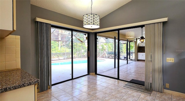 entryway featuring ceiling fan, lofted ceiling, and light tile patterned floors