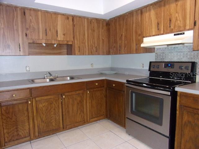 kitchen featuring light tile patterned flooring, decorative backsplash, sink, and stainless steel electric range