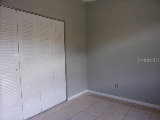 unfurnished bedroom with light tile patterned flooring and a closet