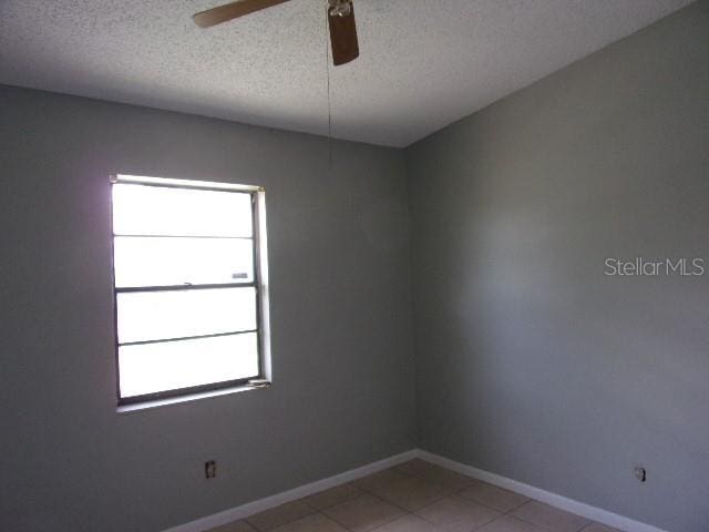 tiled spare room with ceiling fan and a textured ceiling