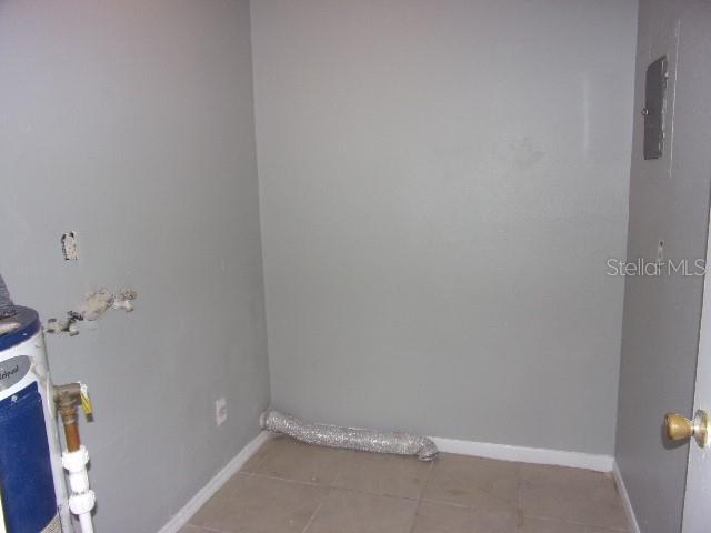 laundry area with tile patterned floors and electric water heater