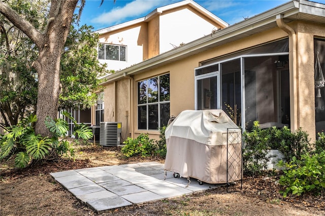 back of property with a sunroom, a patio area, and central air condition unit