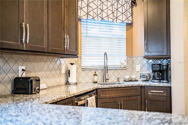 kitchen featuring decorative backsplash, light stone counters, dark brown cabinets, sink, and dishwasher