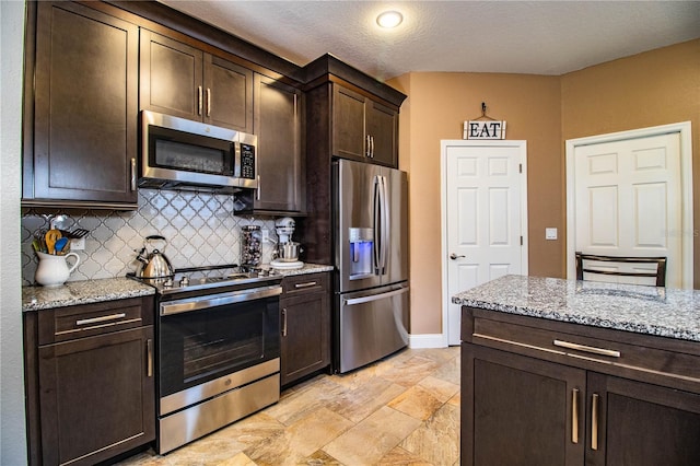 kitchen with light stone countertops, decorative backsplash, dark brown cabinetry, and stainless steel appliances