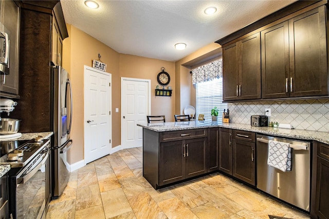 kitchen featuring backsplash, kitchen peninsula, light stone counters, and appliances with stainless steel finishes