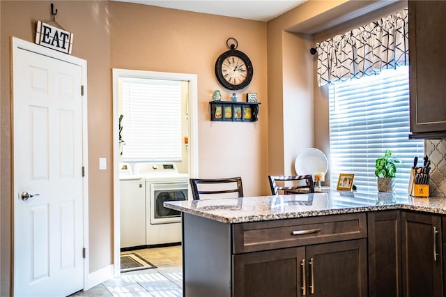 kitchen featuring dark brown cabinetry, light stone countertops, tasteful backsplash, independent washer and dryer, and kitchen peninsula