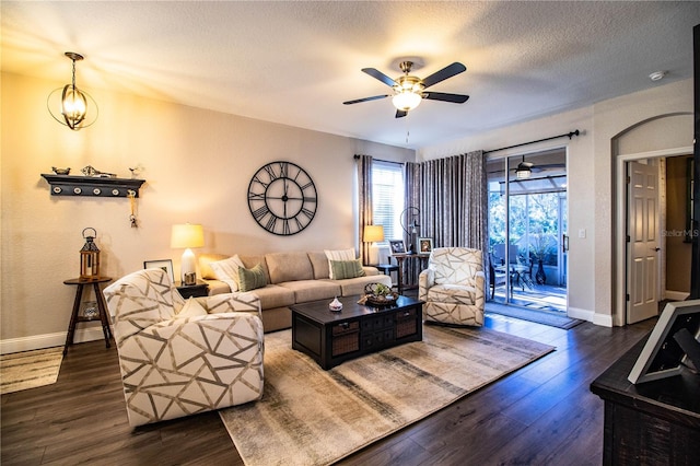 living room featuring ceiling fan with notable chandelier, a textured ceiling, and dark hardwood / wood-style floors