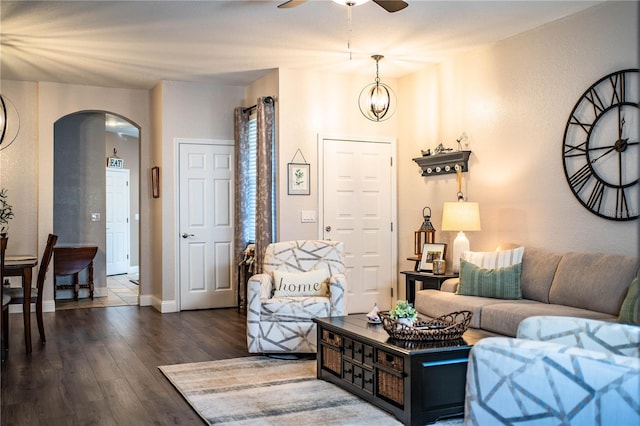 living room featuring ceiling fan with notable chandelier and dark hardwood / wood-style flooring