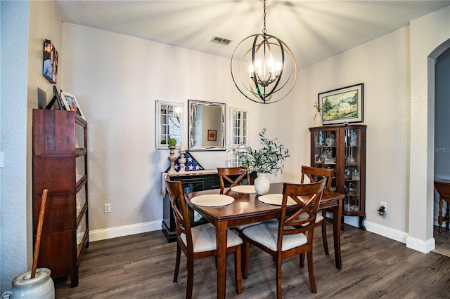 dining space with dark hardwood / wood-style floors and an inviting chandelier