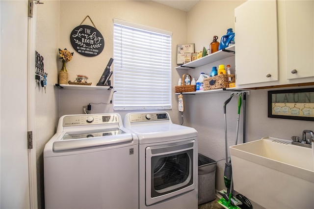 laundry room with washing machine and clothes dryer, cabinets, and sink