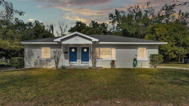 ranch-style home with covered porch and a yard