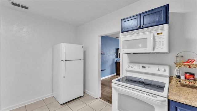 kitchen featuring white appliances, blue cabinets, and light tile patterned flooring