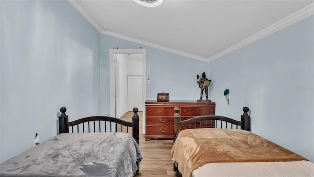 bedroom featuring light wood-type flooring, vaulted ceiling, and ornamental molding