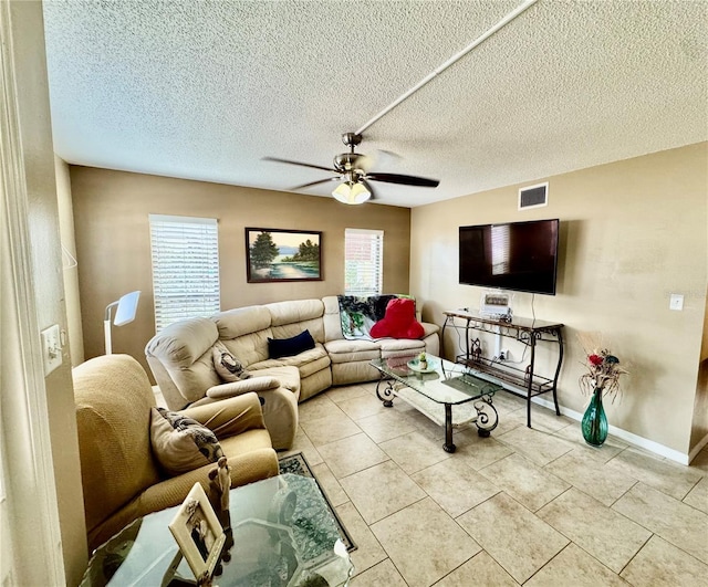 living room featuring ceiling fan, light tile patterned floors, and a textured ceiling