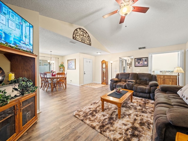 living room with a textured ceiling, lofted ceiling, hardwood / wood-style floors, and ceiling fan with notable chandelier