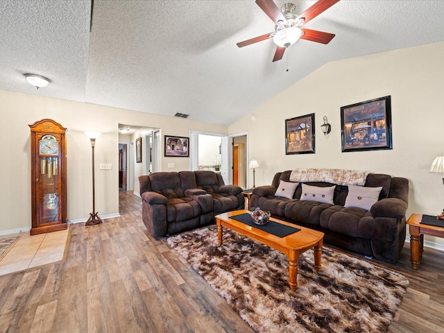 living room with a textured ceiling, hardwood / wood-style flooring, ceiling fan, and lofted ceiling