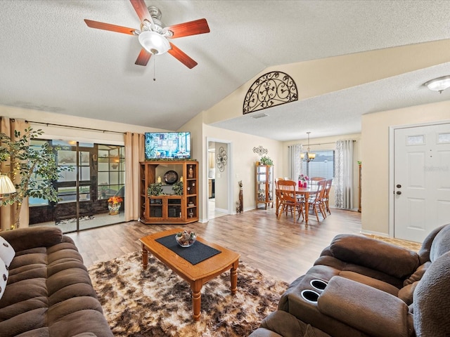 living room with a textured ceiling, ceiling fan with notable chandelier, light hardwood / wood-style floors, and vaulted ceiling