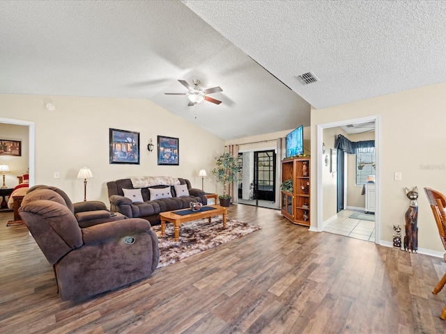 living room with ceiling fan, light wood-type flooring, a textured ceiling, and lofted ceiling