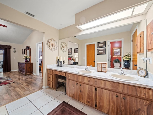 bathroom with tile patterned flooring, vanity, and lofted ceiling