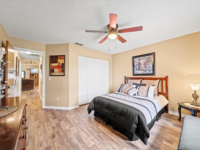 bedroom with ceiling fan, light hardwood / wood-style floors, a textured ceiling, and a closet