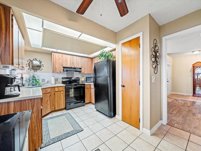 kitchen featuring ceiling fan, sink, a textured ceiling, light tile patterned floors, and black appliances