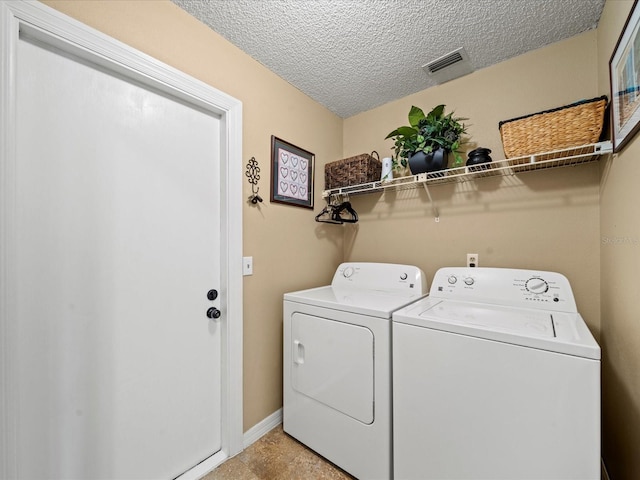 washroom with a textured ceiling and independent washer and dryer