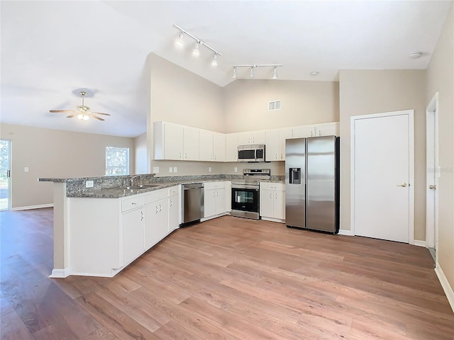 kitchen featuring light stone countertops, white cabinets, stainless steel appliances, sink, and kitchen peninsula