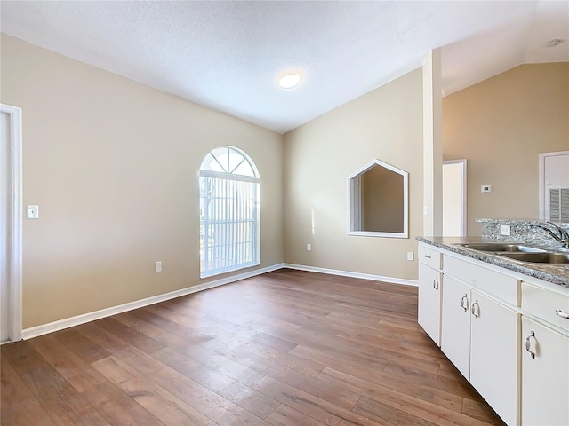 kitchen with vaulted ceiling, sink, white cabinetry, and light hardwood / wood-style flooring