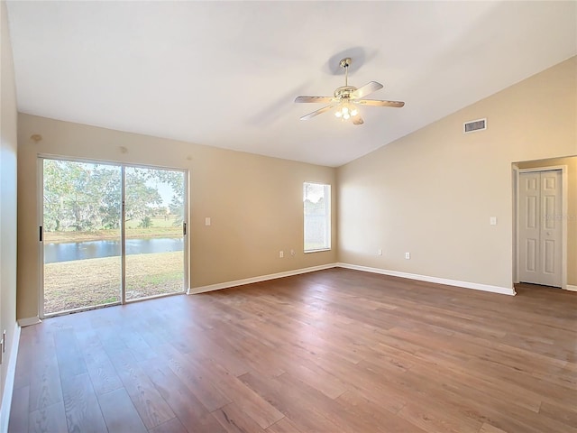 spare room featuring ceiling fan, vaulted ceiling, a water view, and hardwood / wood-style floors