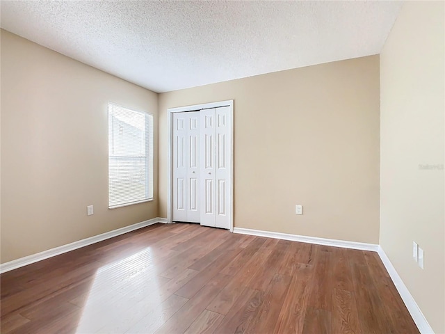 unfurnished bedroom with a closet, a textured ceiling, and hardwood / wood-style flooring