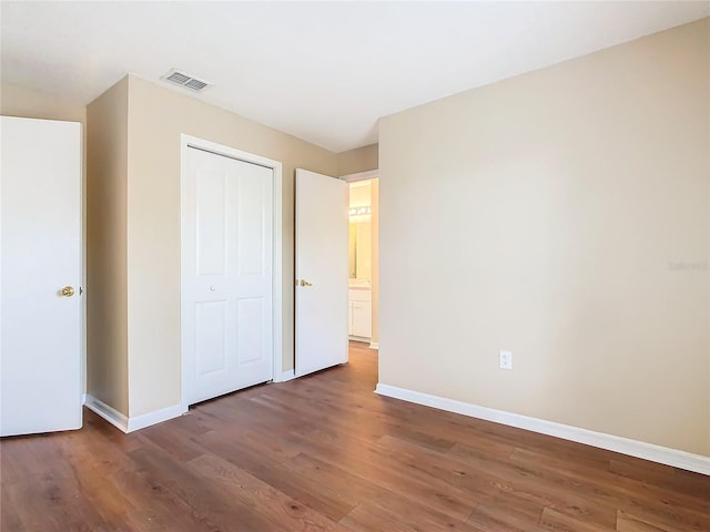 unfurnished bedroom with a closet and dark hardwood / wood-style floors