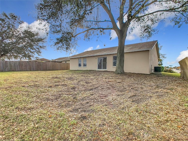 rear view of property with cooling unit and a lawn