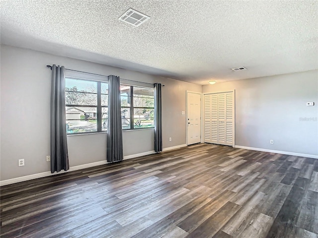 spare room with a textured ceiling and dark hardwood / wood-style floors