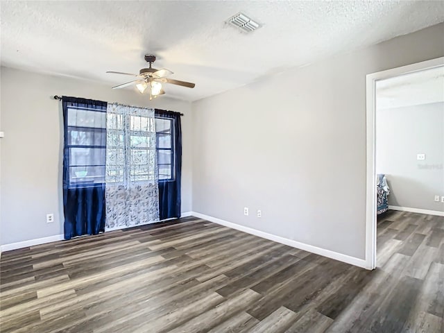 empty room with dark hardwood / wood-style floors, ceiling fan, and a textured ceiling