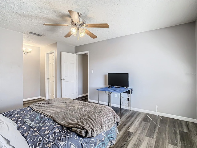 bedroom with a textured ceiling, dark hardwood / wood-style flooring, and ceiling fan