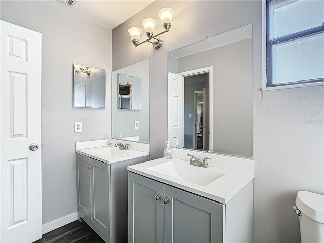 bathroom featuring hardwood / wood-style flooring, vanity, a chandelier, and toilet