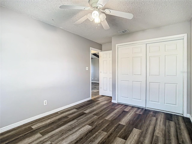 unfurnished bedroom with ceiling fan, a closet, dark wood-type flooring, and a textured ceiling