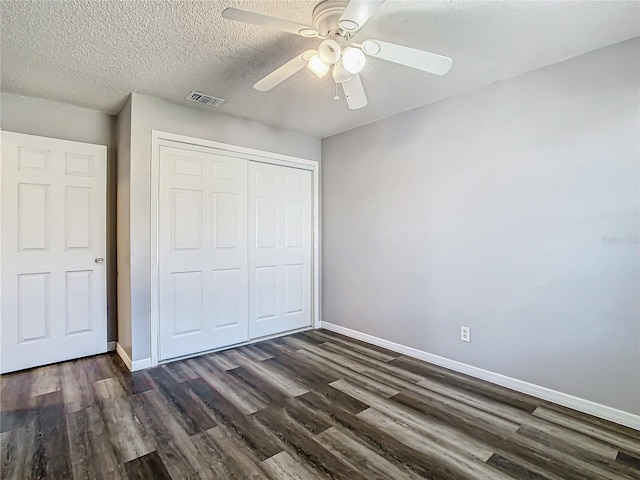 unfurnished bedroom featuring dark hardwood / wood-style flooring, ceiling fan, a closet, and a textured ceiling