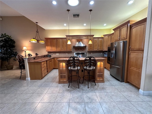 kitchen with a center island with sink, hanging light fixtures, a breakfast bar area, stainless steel appliances, and dark stone countertops