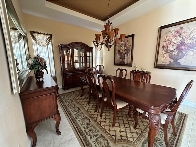 tiled dining area featuring a tray ceiling, a chandelier, and a healthy amount of sunlight