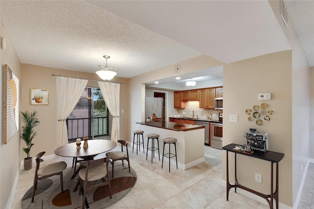 kitchen with sink, stainless steel appliances, kitchen peninsula, pendant lighting, and decorative backsplash