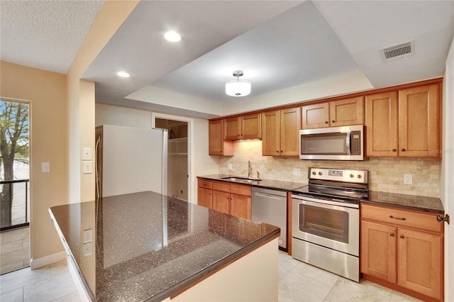 kitchen with backsplash, dark stone countertops, sink, and stainless steel appliances