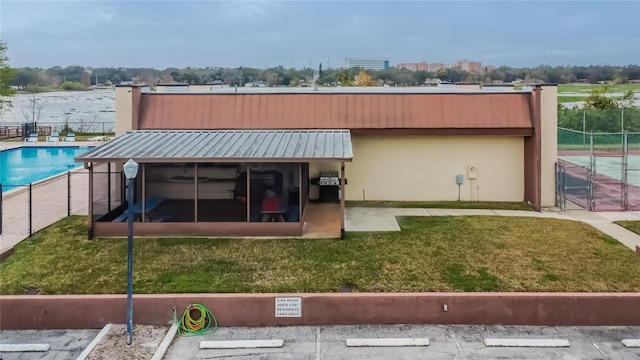 back of property featuring a lawn, fence, and a sunroom