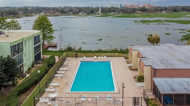 community pool featuring a patio, a water view, and fence