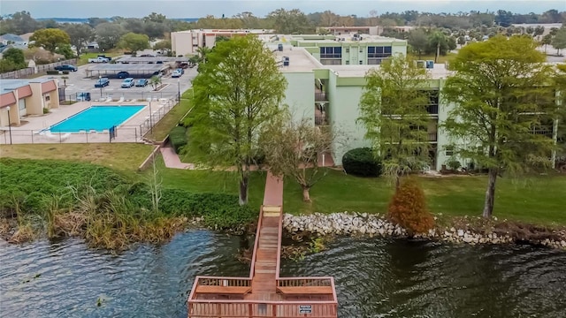 exterior space featuring a water view, a pool, and a lawn