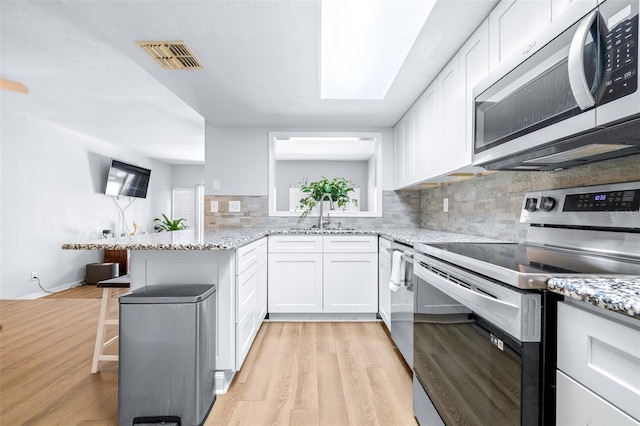 kitchen featuring white cabinets, sink, kitchen peninsula, and stainless steel appliances