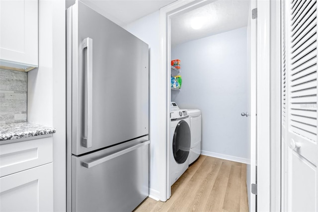 laundry room featuring washing machine and dryer and light hardwood / wood-style flooring