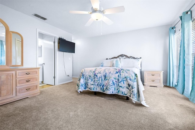 bedroom with ceiling fan, light carpet, and ensuite bath