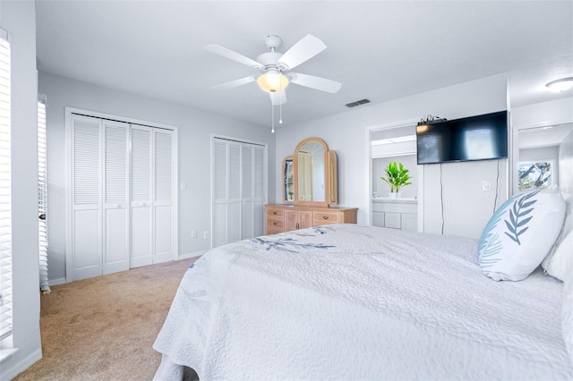 carpeted bedroom featuring ceiling fan and multiple closets